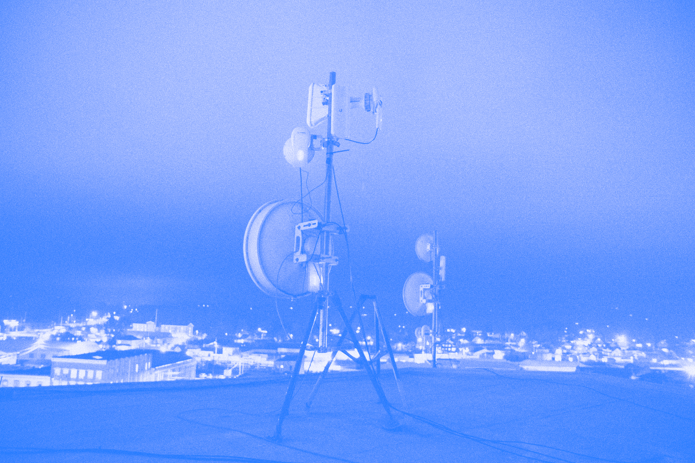 A stylized photograph of Althea telecommunications antennae on an urban rooftop at night.
